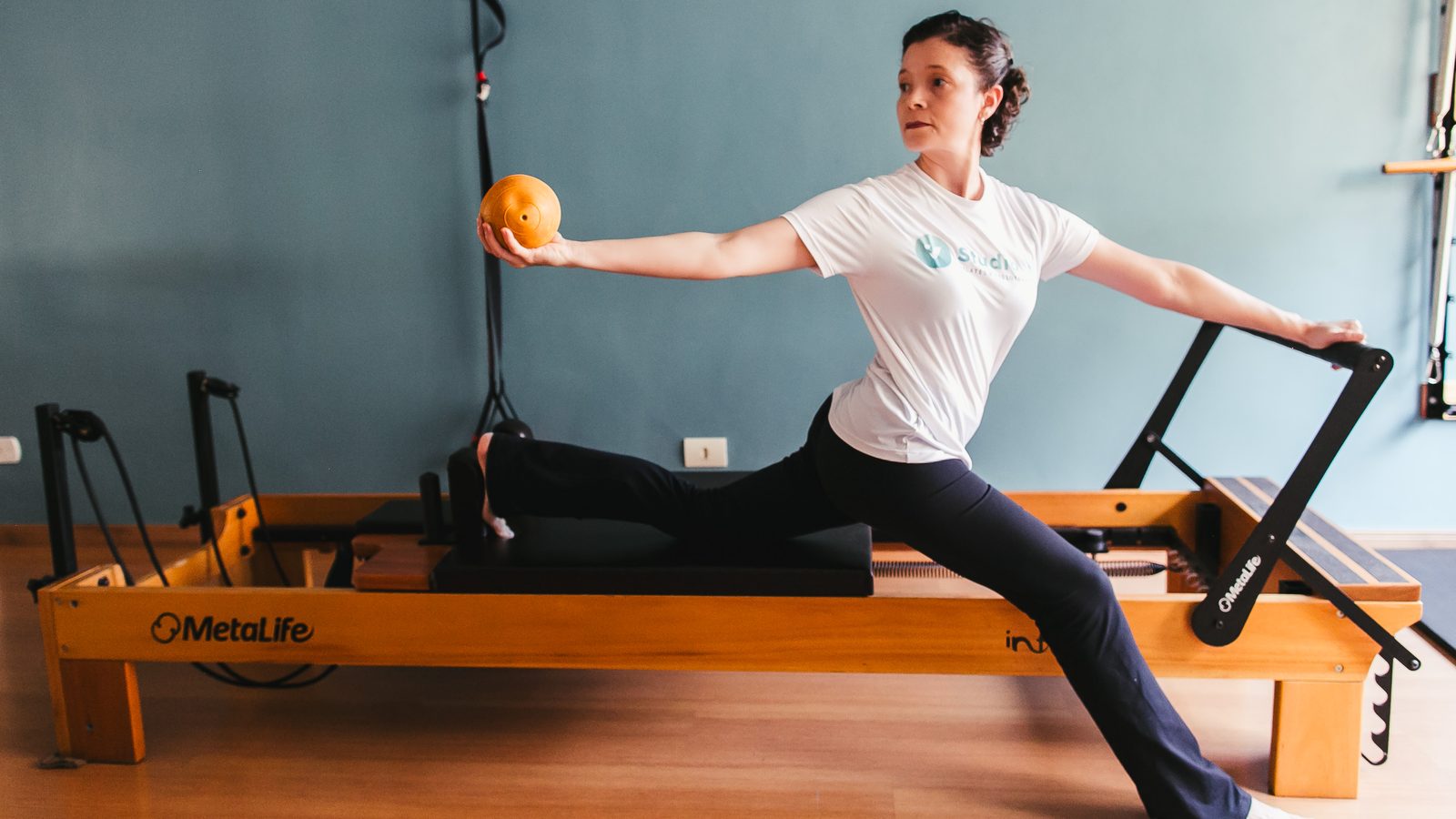 Aluna em exercício de equilíbrio e força no Reformer