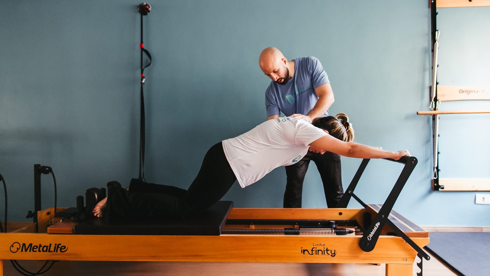 Professor acompanhando uma aluna durante o exercício no Reformer